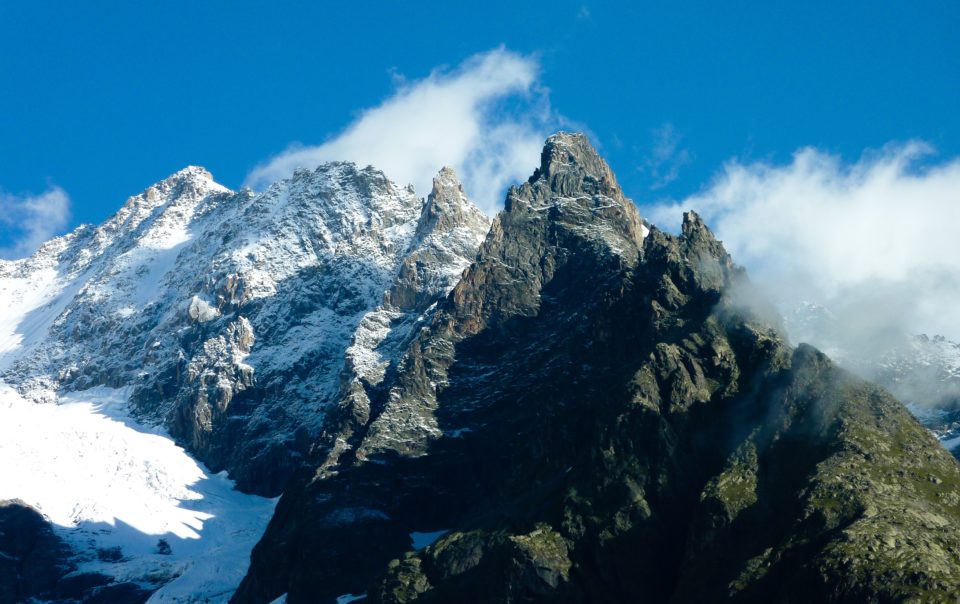 Un sommet montagneux enneigé émergeant sous un ciel bleu, symbolisant les sommets atteints par une gestion optimale des émissions industrielles.