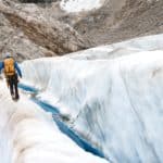 Un professionnel équipé avance avec prudence le long d’une crevasse, symbole des risques aérauliques à contenir et de la conformité qu'il doit garantir