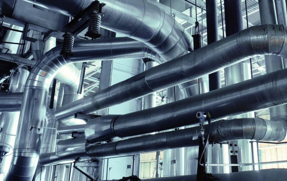Vue de réseaux aérauliques industriels complexes dans une installation technique.